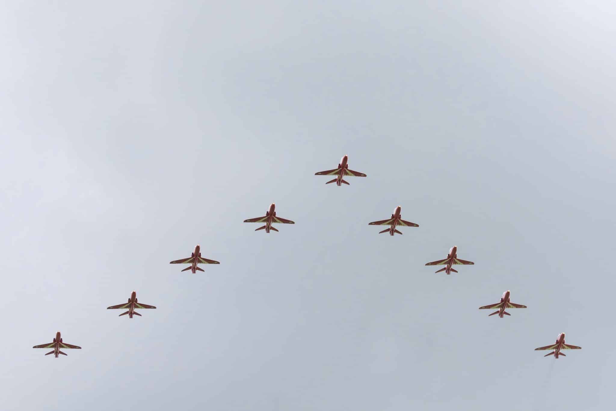 A striking image of red jets flying in a perfect V formation against a clear sky.