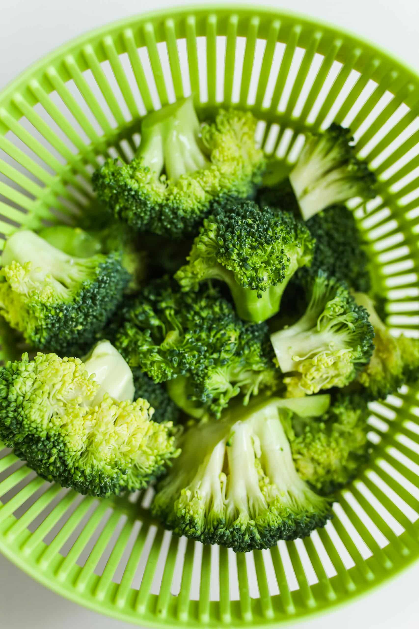 Vibrant fresh broccoli florets in a green colander, perfect healthy ingredient